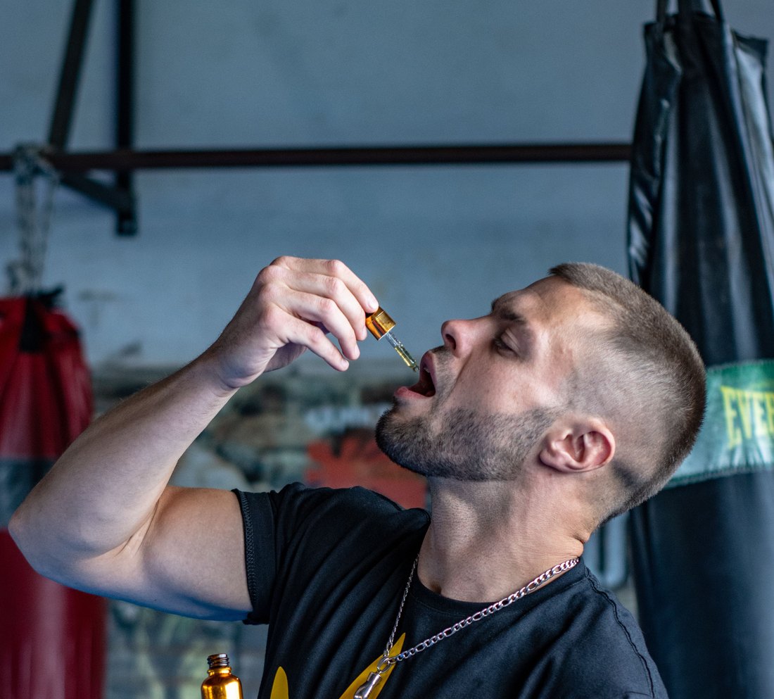 Athlete taking a sublingual dropper dose in a gym
