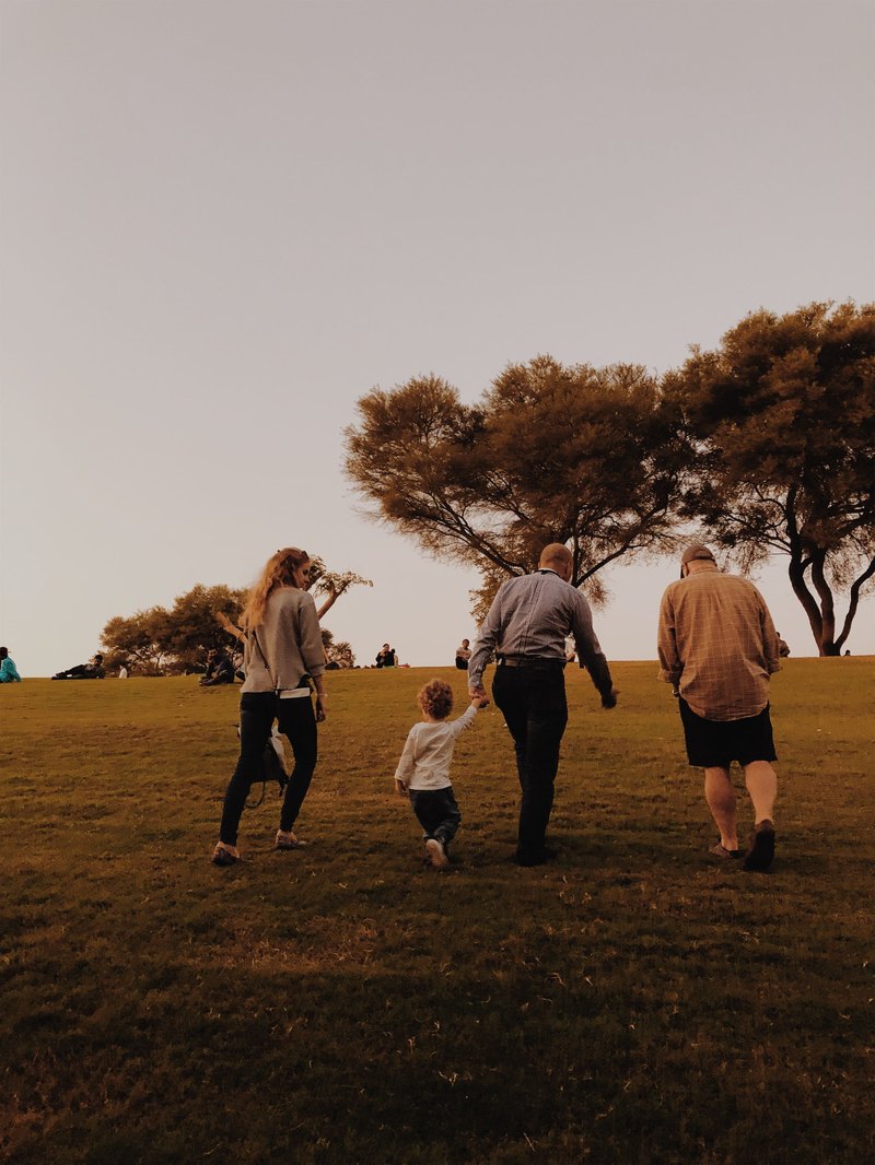 A family walking together across open grass at sunset